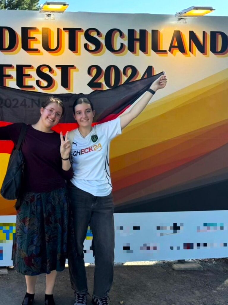 Zwei Mädchen vor einem Plakat zum Deutschlandfest 2024 in Japan