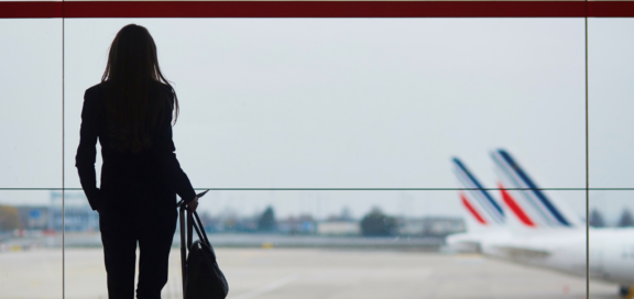 Junge Frau von hinten am Flughafen, Flugzeuge im Hintergrund