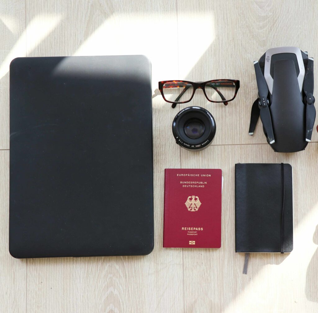 reiseutensilien wie terminplaner, brille und reisepass liegen nebeneinander auf dem boden