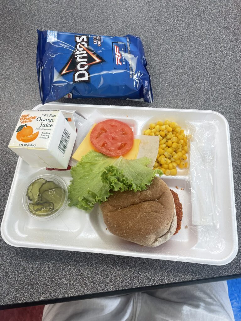 tablett mit schulessen - burger, mais und orangensaft