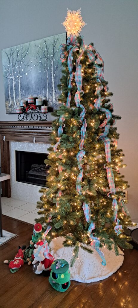 Schmaler, leuchtender Weihnachtsbaum vor dem Kamin im Wohnzimmer