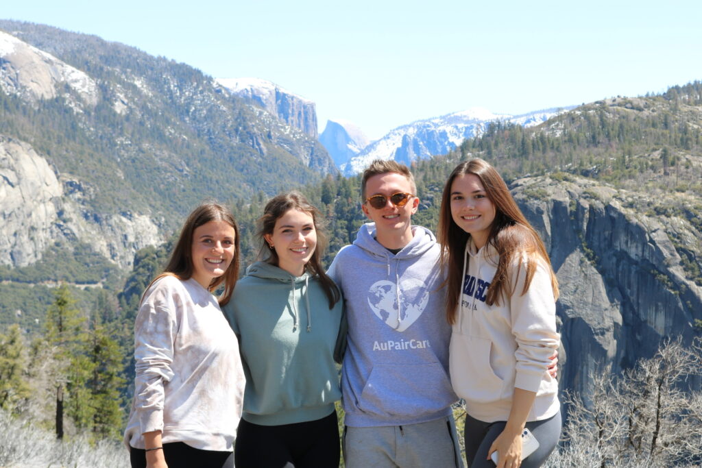 Gruppe von vier Au pairs posieren vor dem Hintergrund einer Bergkulisse