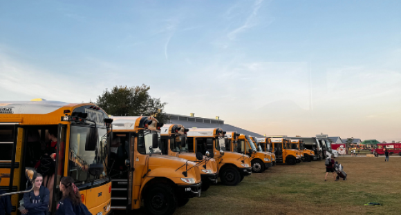 Gelbe Schulbusse in einer Reihe auf der Wiese